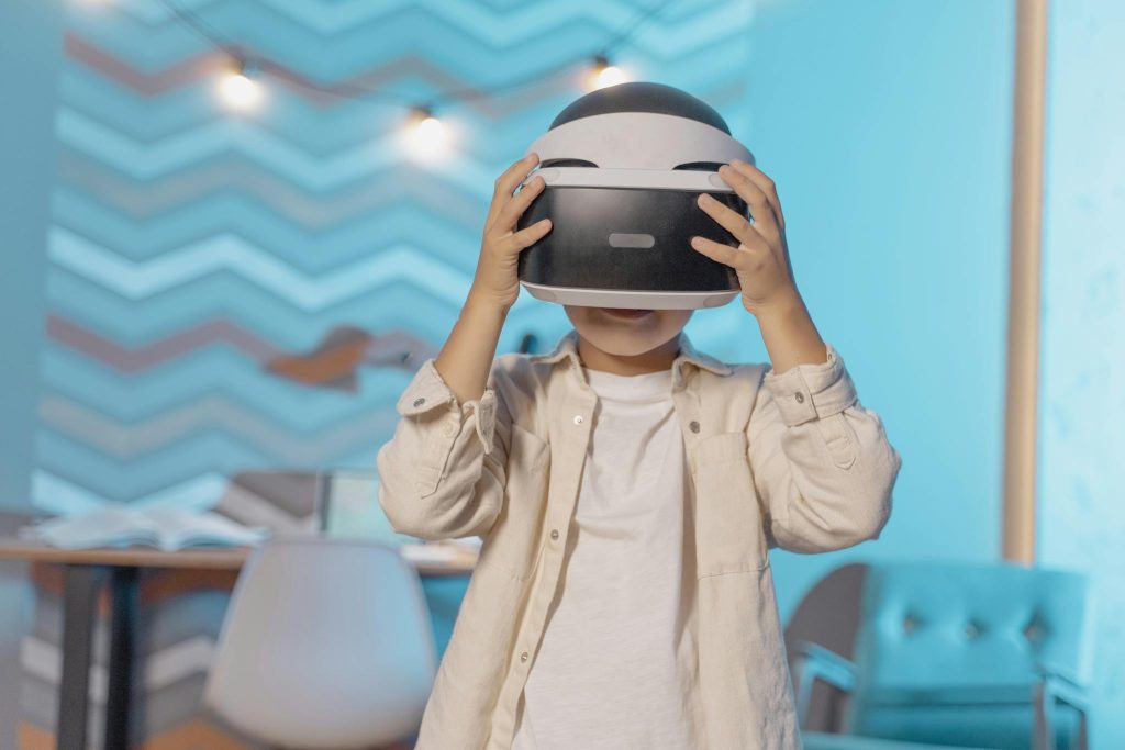 Young boy exploring virtual reality with VR goggles indoors, enjoying technology in a cozy setting.